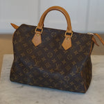 Designer handbag with monogram pattern on a textured wall